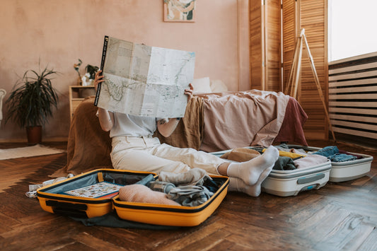 a woman holding a map sitting on the floor with suitcases.