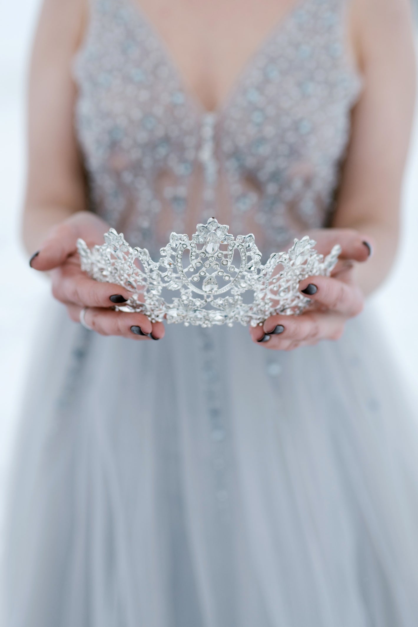 A woman wearing blue dress holding a tiara