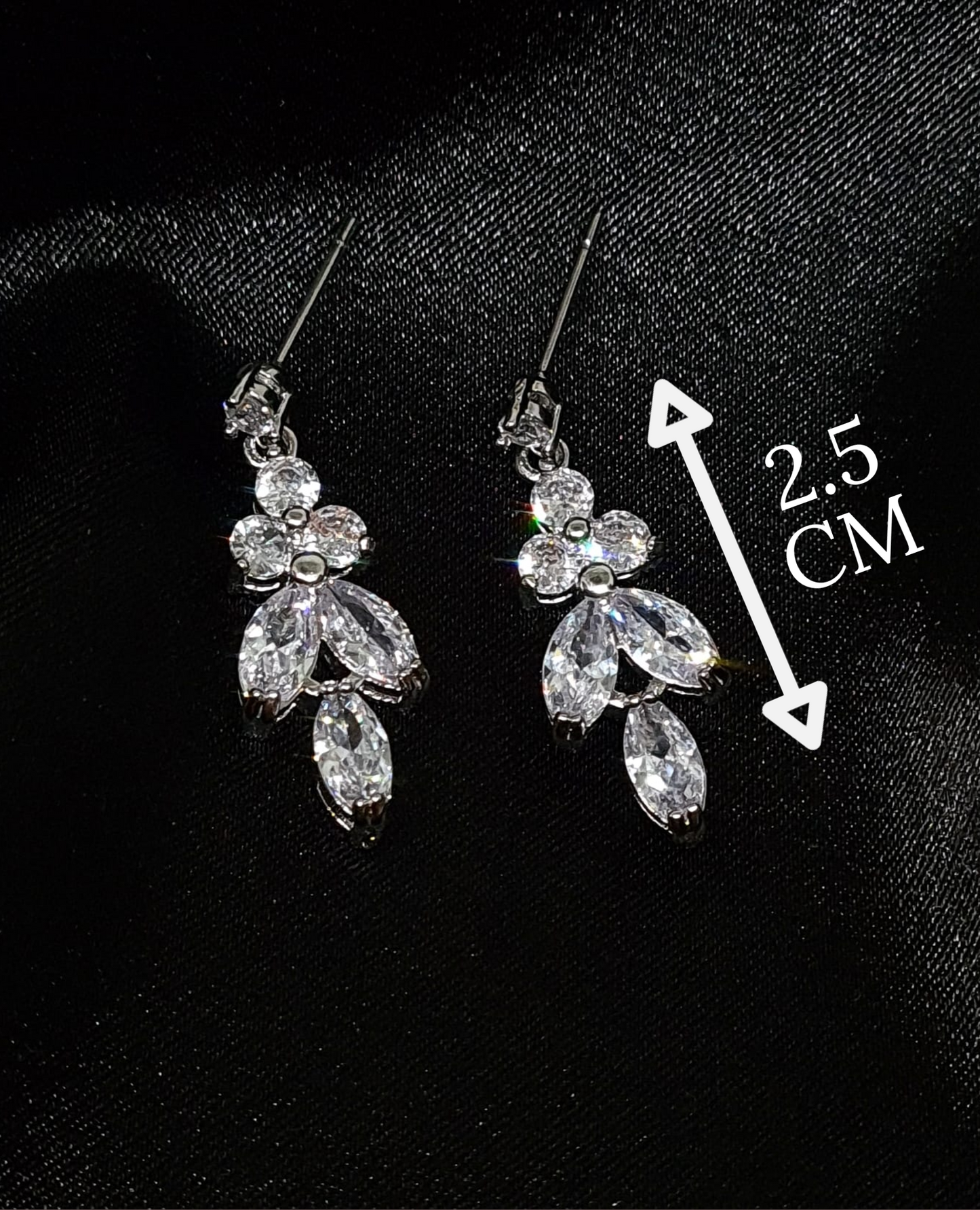 A close-up of a pair of silver earrings with cubic zirconia. The earrings are simple in design, with a modern twist. The cubic zirconia are sparkling and the earrings are a perfect accessory for a special occasion or a gift for a loved one. with measures.