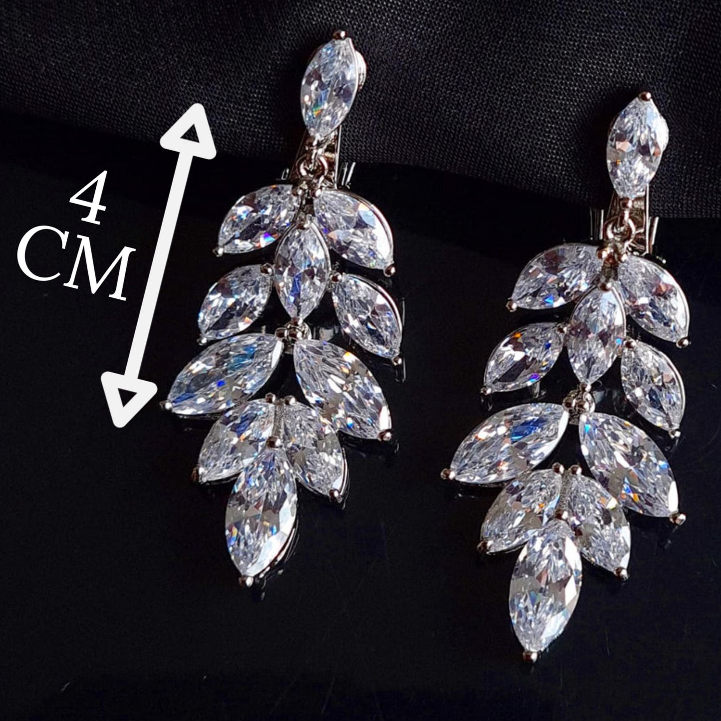 A pair of silver earrings with cubic zirconia. The earrings are simple in design and the cubic zirconia are sparkling. The earrings are a perfect accessory for a special occasion or a gift for a loved one. with measures.