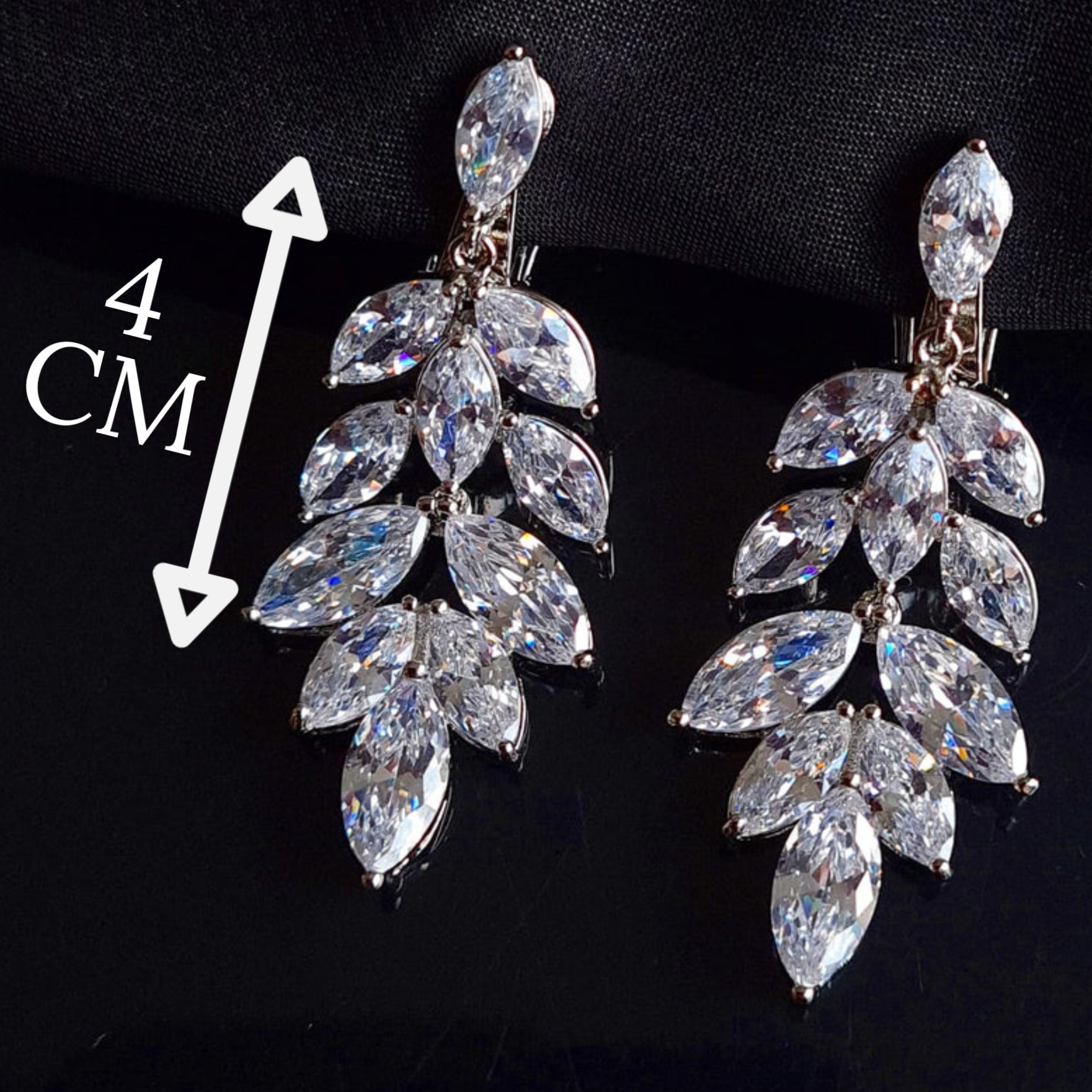 A pair of silver earrings with cubic zirconia. The earrings are simple in design and the cubic zirconia are sparkling. The earrings are a perfect accessory for a special occasion or a gift for a loved one. with measures.