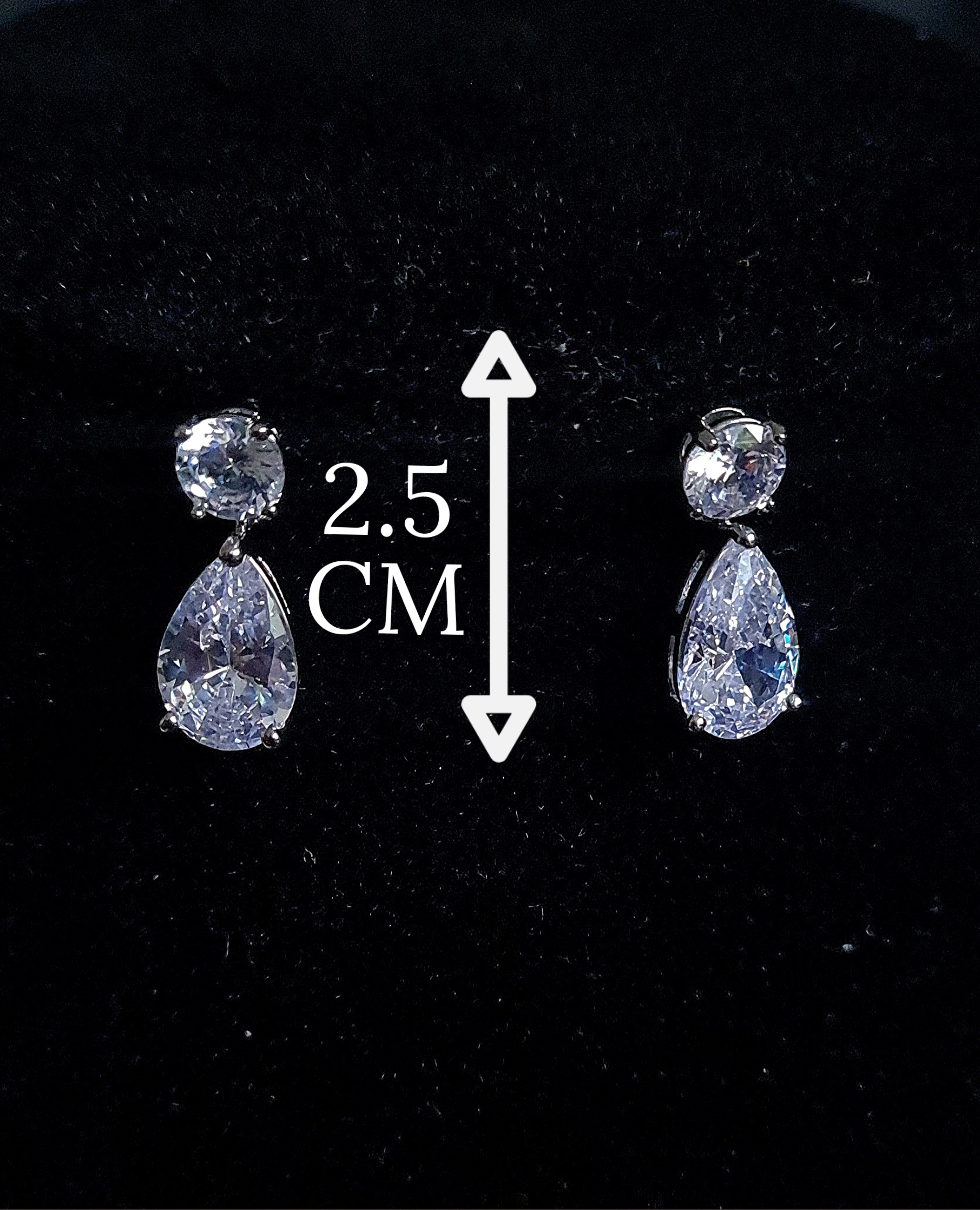 A pair of mini earrings studded with cubic zirconia crystals Placed on black table.
