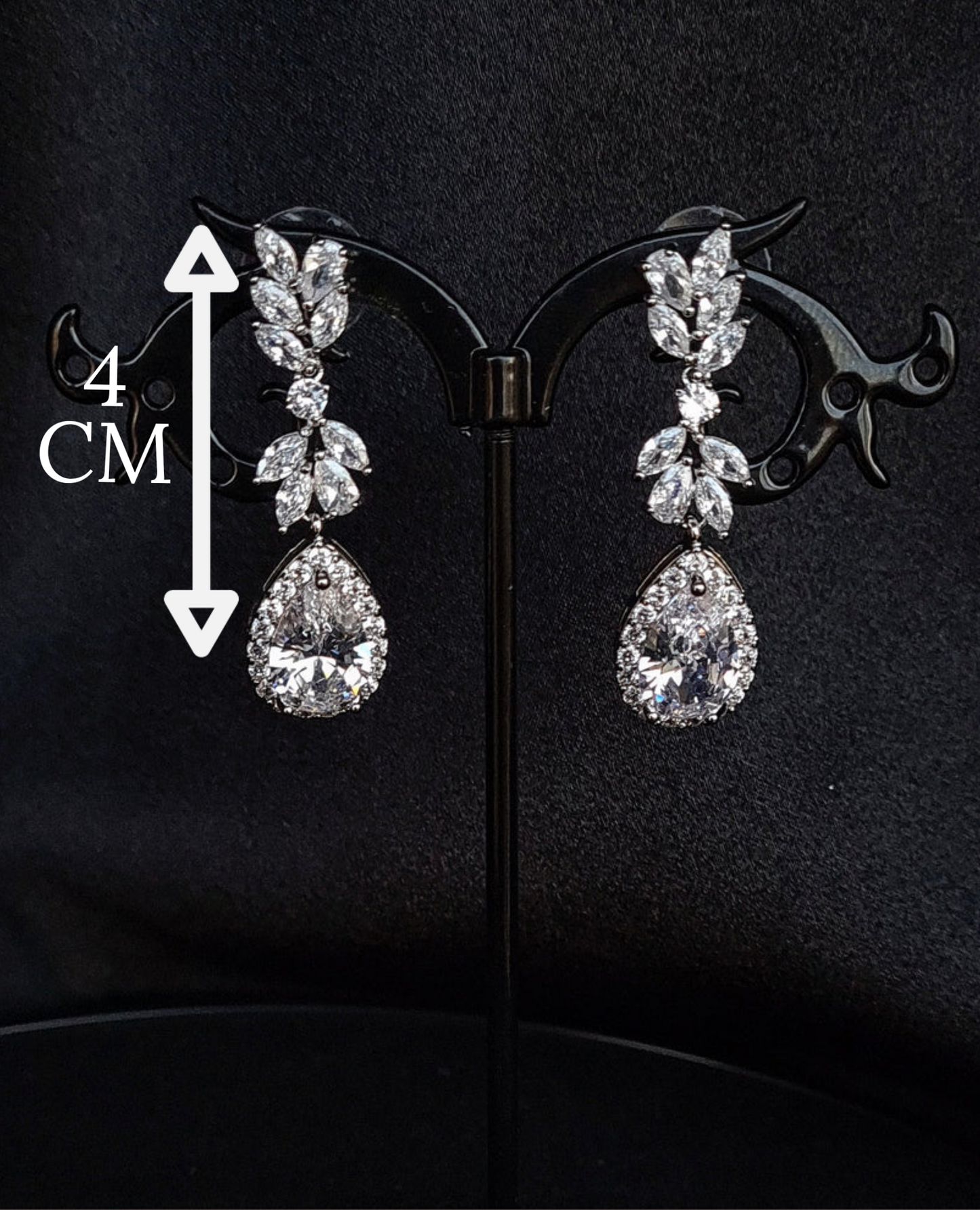 A pair of silver earrings with dangling teardrop pearls. The earrings are simple in design and the pearls are lustrous. The earrings are a perfect accessory for a special occasion or a gift for a loved one. with measures.