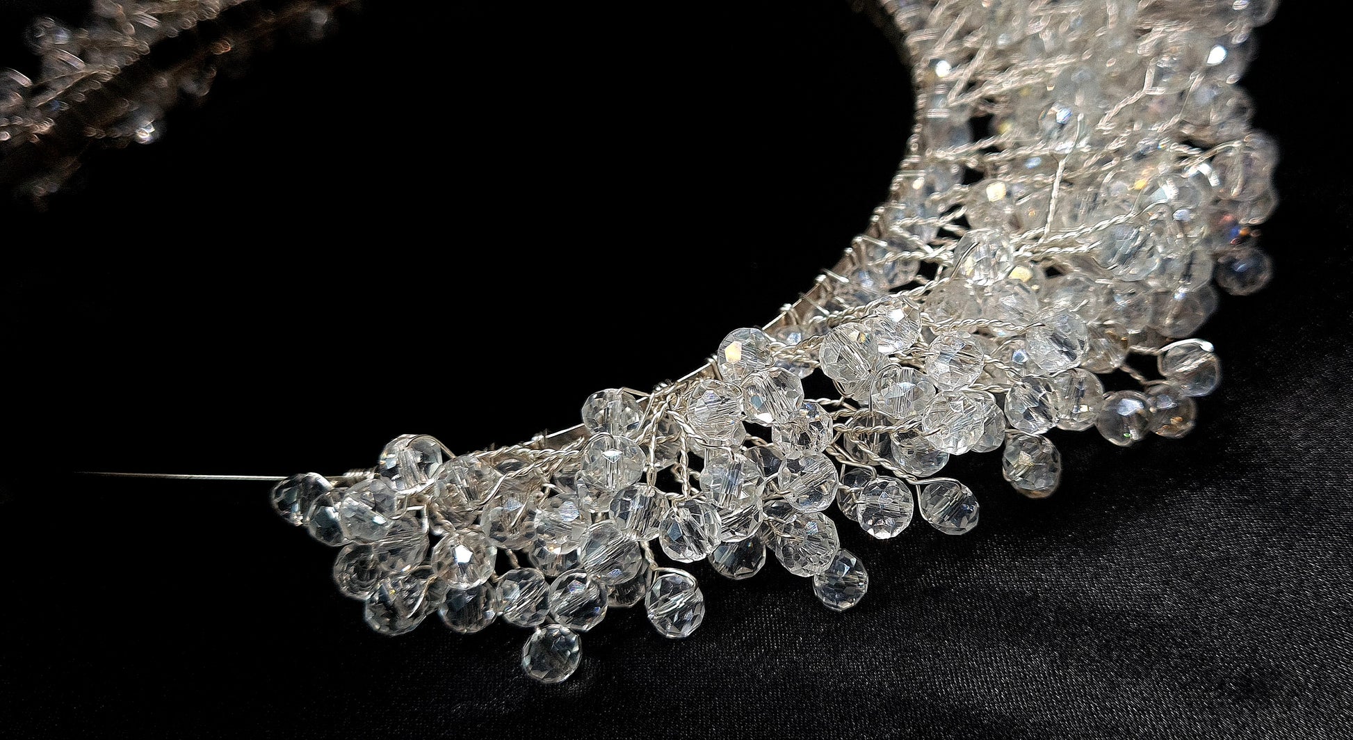 a bridal hair piece on a black background. The hair piece is made of pearls and crystals, and it has a delicate, feminine design. It is perfect for a bride who wants to add a touch of elegance to her wedding day look. The hair piece is shown on a black background, so the pearls and crystals stand out beautifully