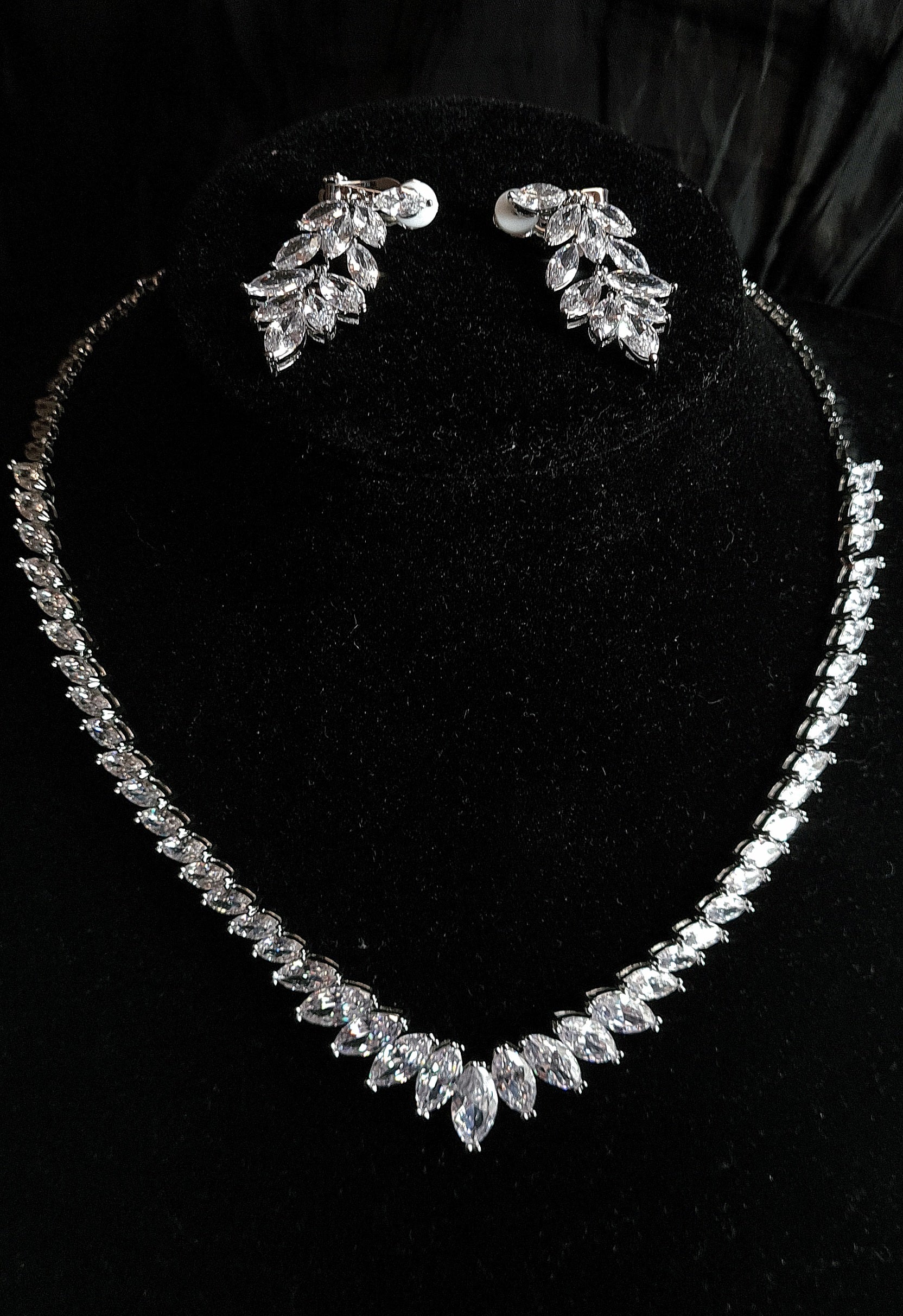 Black Mannequin Displaying a Stylish Cubic Zirconia Necklace and Earring Jewelry Set with Marquise Cut Design. The Necklace Showcases a Brilliant Marquise Shape Cut CZ Pendant, Complemented by Dangle Drop Earrings of Matching Design. All Set Against a Sleek Black Background,