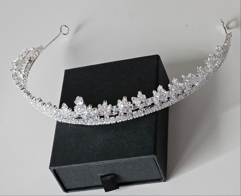 An editorial-style angled shot of a silver-toned wedding tiara with marquise-cut crystal clusters, highlighting the delicate craftsmanship of the high-status headpiece.