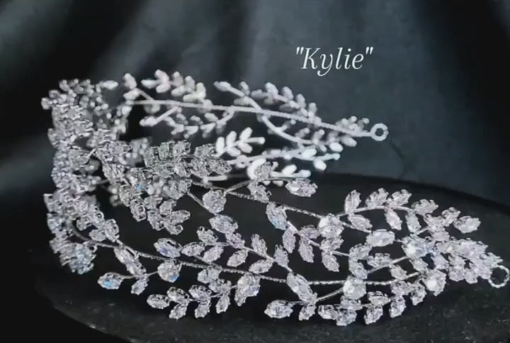 a bridal hairpiece with double rows of cubic zirconia on a black background. The hairpiece is made of cubic zirconia and has a delicate, feminine design. It is perfect for a bride who wants to add a touch of elegance to her wedding day look. The hairpiece is shown on a black background, so the cubic zirconia stands out beautifully