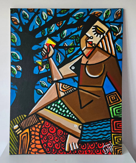 A woman with bold features sits under a leafy tree, holding a drink and exuding a sense of tranquility.