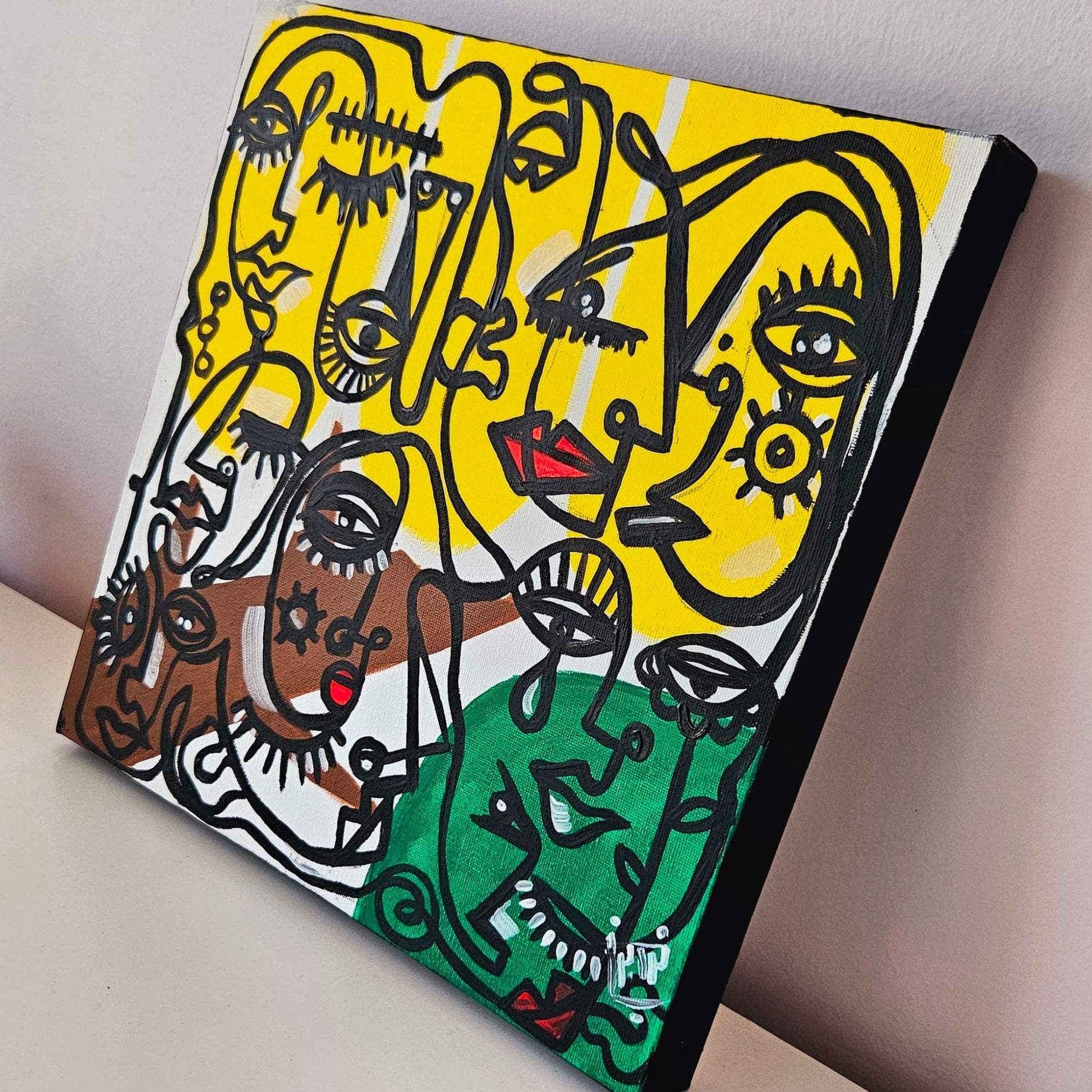 Vibrant abstract painting featuring multiple stylized faces with bold colors and black linework, set against a yellow background.