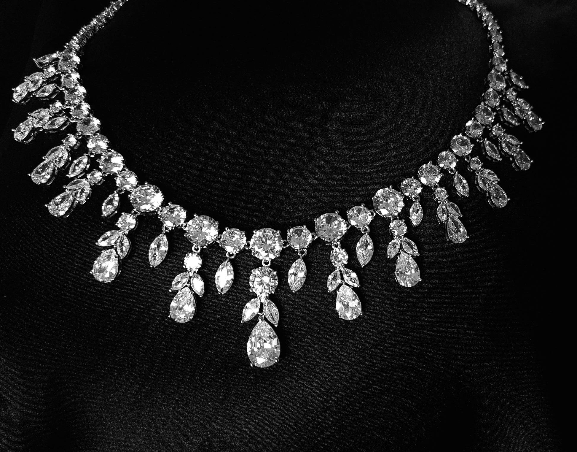 Close-up view of a diamond necklace sparkling with zirconia Diamonds displayed on a black table.  the stones are teardrop shape