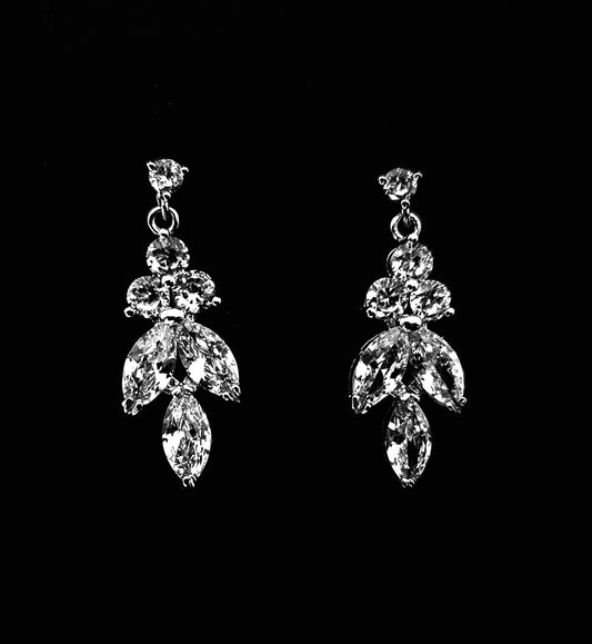 A close-up of a pair of silver earrings with cubic zirconia. The earrings are simple in design, with a modern twist. The cubic zirconia are sparkling and the earrings are a perfect accessory for a special occasion or a gift for a loved one.
