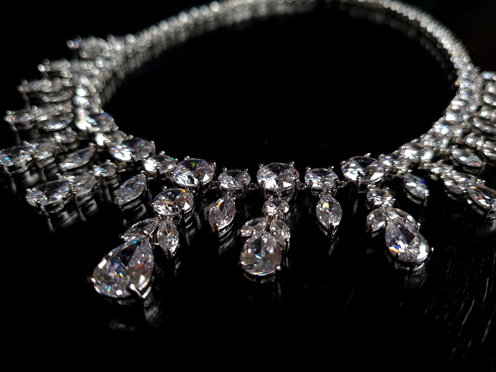 Close-up view of a diamond necklace sparkling with zirconia Diamonds displayed on a black table.