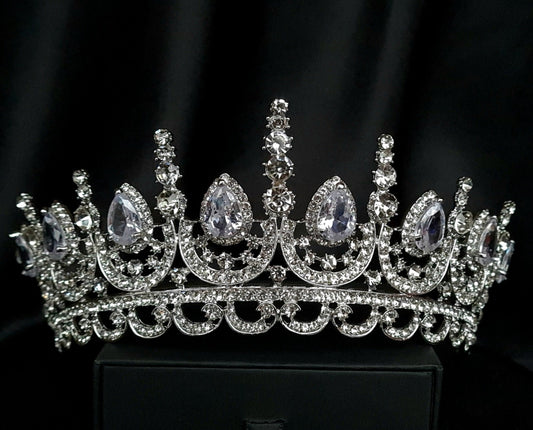 A close-up of a tiara made of cubic zirconia. The tiara is silver in color and has a cascading design. It is decorated with clear cubic zirconia stones that sparkle in the light.