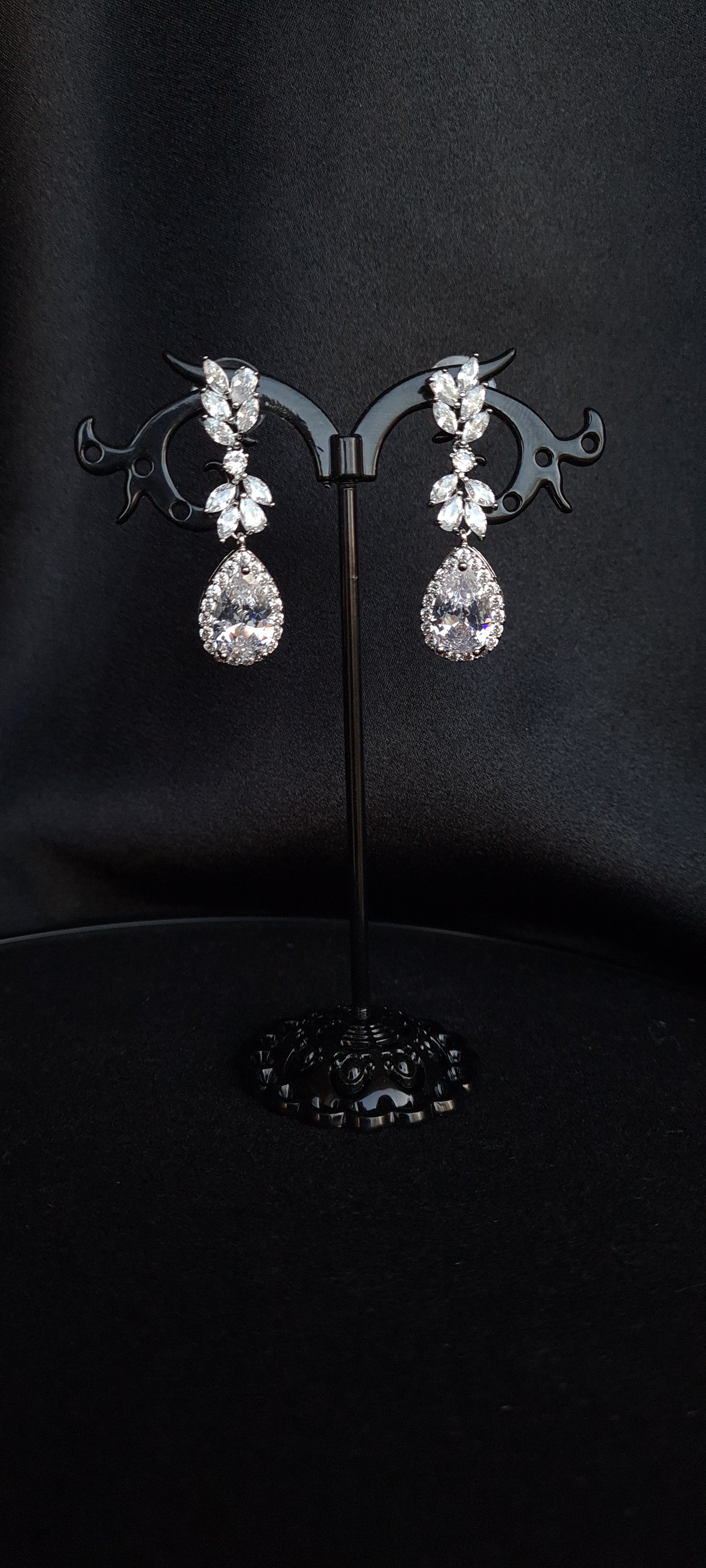 A pair of silver earrings with dangling teardrop pearls. The earrings are simple in design and the pearls are lustrous. The earrings are a perfect accessory for a special occasion or a gift for a loved one.