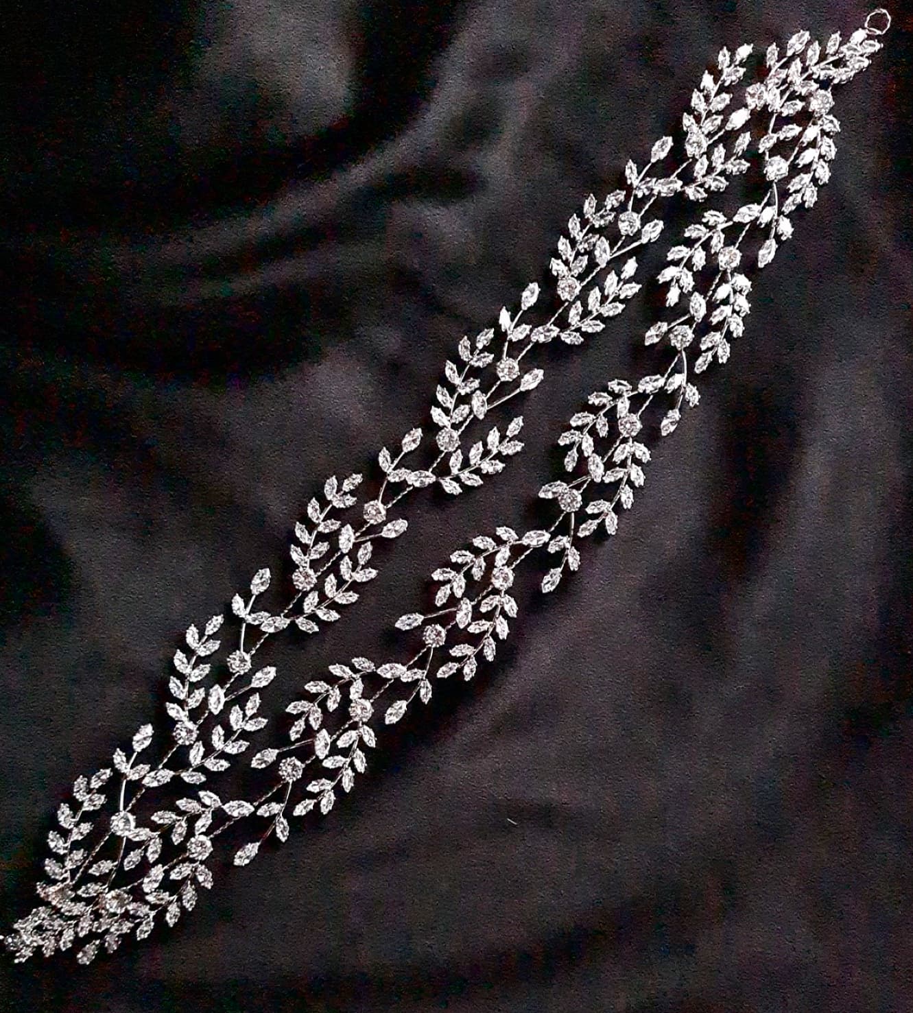 a bridal hairpiece with double rows of cubic zirconia on a black background. The hairpiece is made of cubic zirconia and has a delicate, feminine design. It is perfect for a bride who wants to add a touch of elegance to her wedding day look. The hairpiece is shown on a black background, so the cubic zirconia stands out beautifully