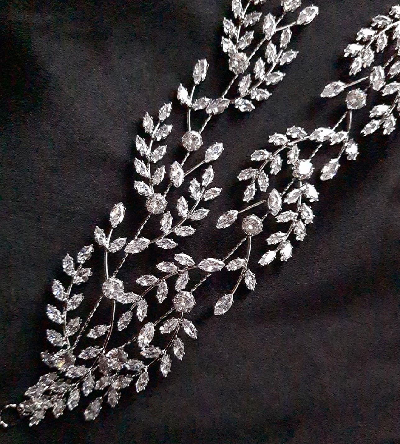 a bridal hairpiece with double rows of cubic zirconia on a black background. The hairpiece is made of cubic zirconia and has a delicate, feminine design. It is perfect for a bride who wants to add a touch of elegance to her wedding day look. The hairpiece is shown on a black background, so the cubic zirconia stands out beautifully