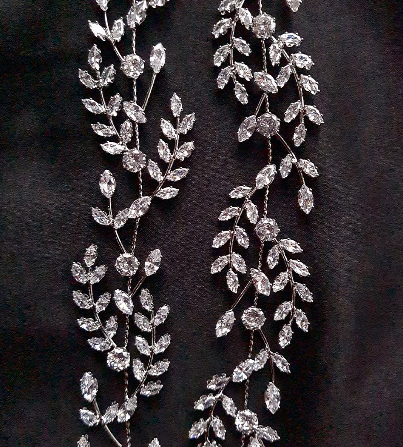 a close up view of a bridal hairpiece with double rows of cubic zirconia on a black background. The hairpiece is made of cubic zirconia and has a delicate, feminine design. It is perfect for a bride who wants to add a touch of elegance to her wedding day look. The hairpiece is shown on a black background, so the cubic zirconia stands out beautifully.