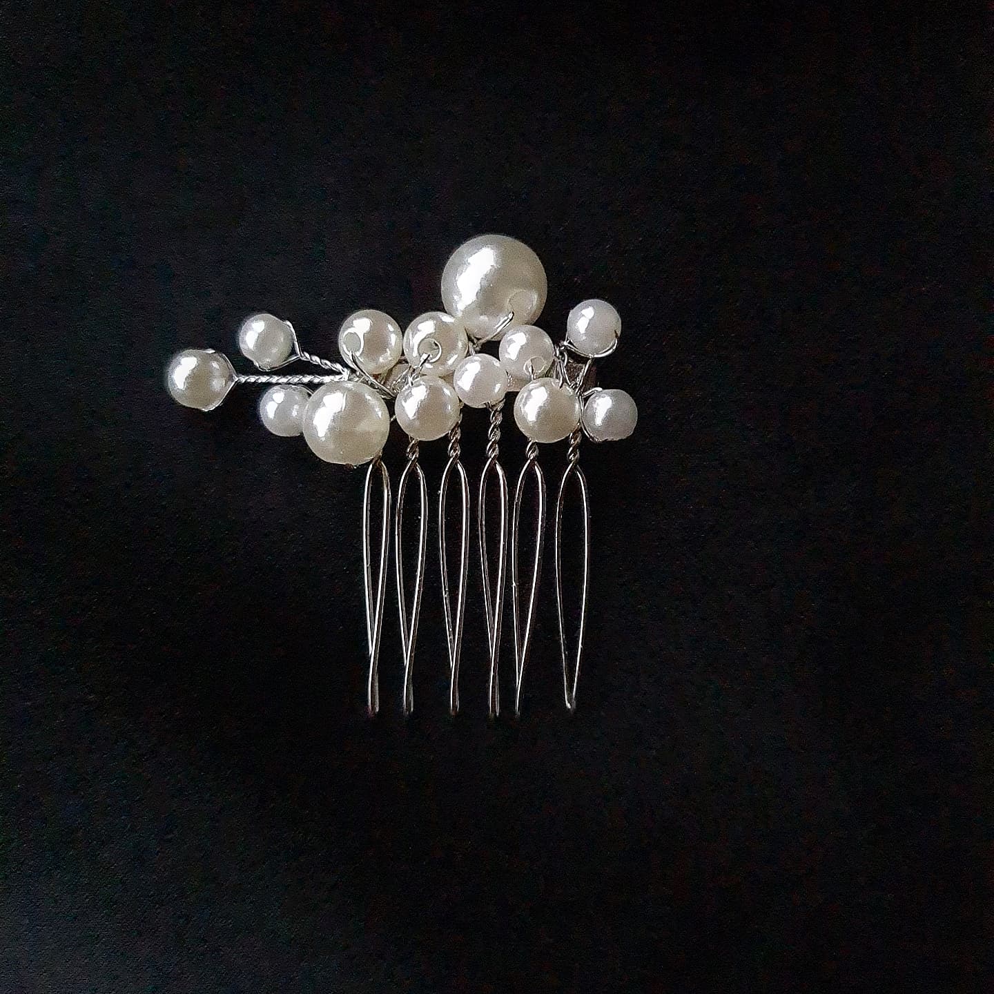 a hair pins with pearls on them. The hair pin is made of metal and have pearls of different sizes on them. The hair pin is in white color.
