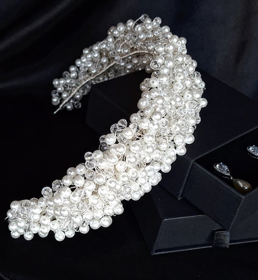 A wedding hair accessory made of pearls and crystals. The headband has a delicate design with pearls and crystals.
