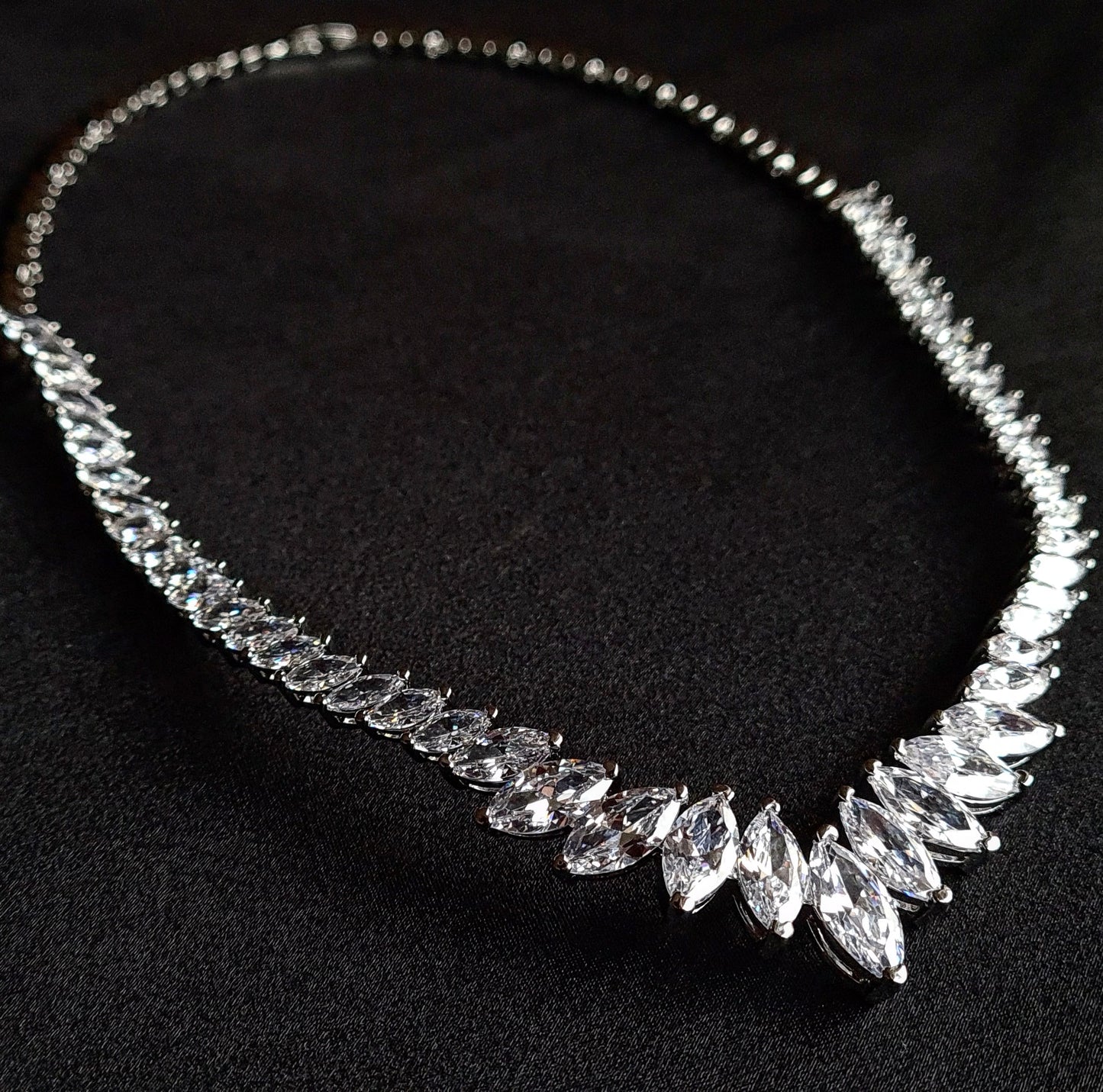 Sparkling cubic zirconia necklace with marquise cut stones on mannequin. The necklace is made up of a single row of marquise-cut cubic zirconia stones, which are sparkling and eye-catching. The necklace is perfect for a special occasion, such as a wedding or prom. It is also a great gift for a loved one.