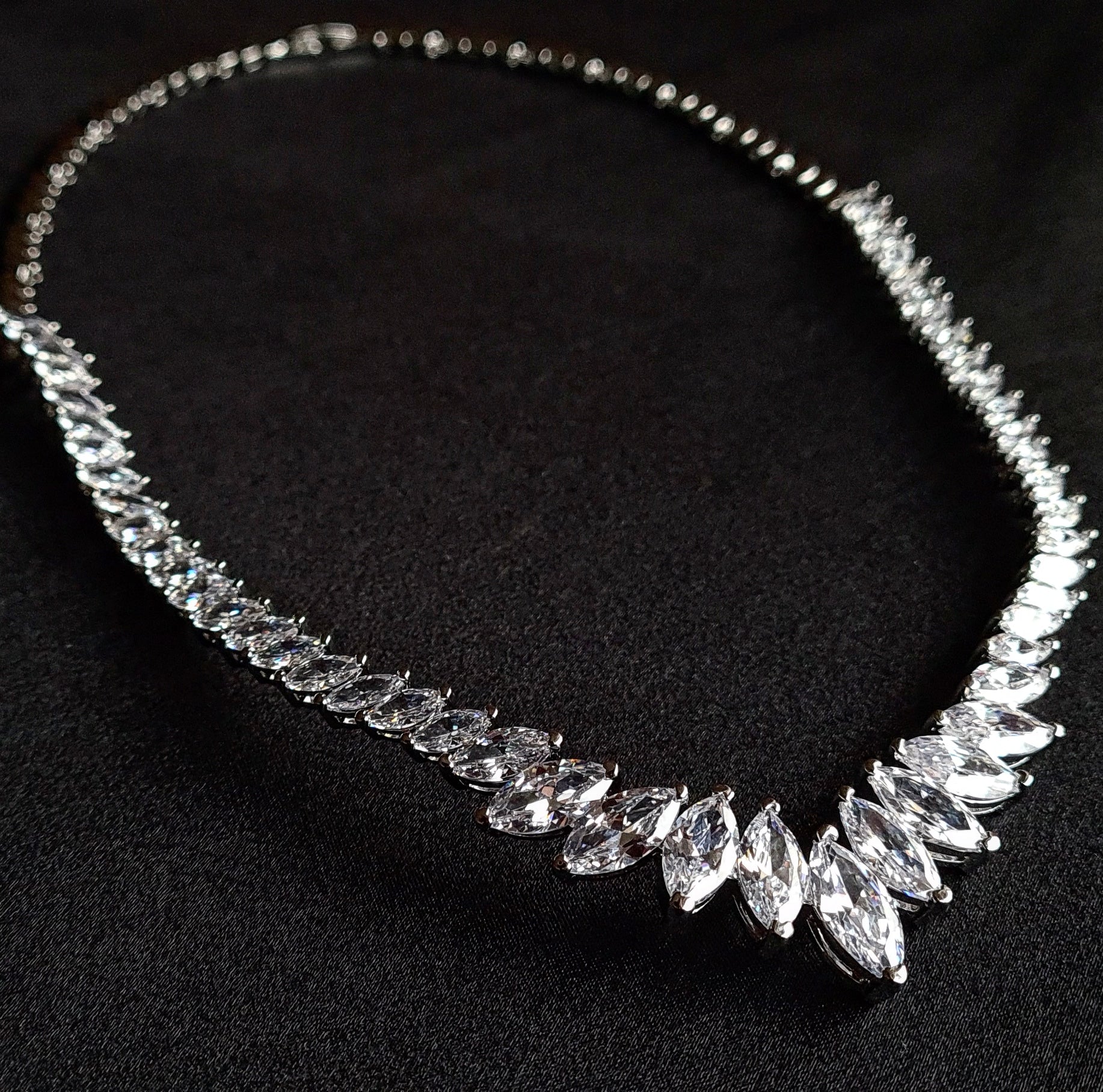 Sparkling cubic zirconia necklace with marquise cut stones on mannequin. The necklace is made up of a single row of marquise-cut cubic zirconia stones, which are sparkling and eye-catching. The necklace is perfect for a special occasion, such as a wedding or prom. It is also a great gift for a loved one.