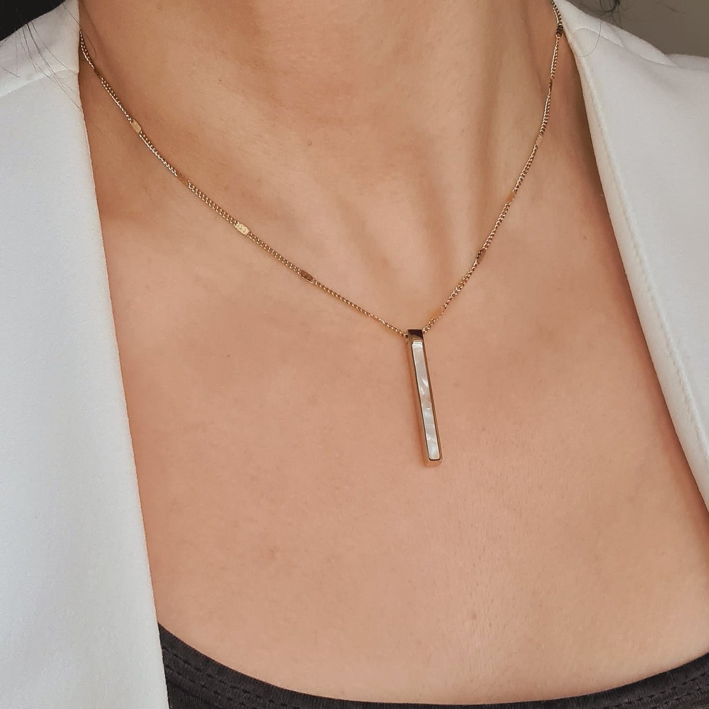 Ayla Necklace a sleek and delicate golden chain with a long shell pendant.