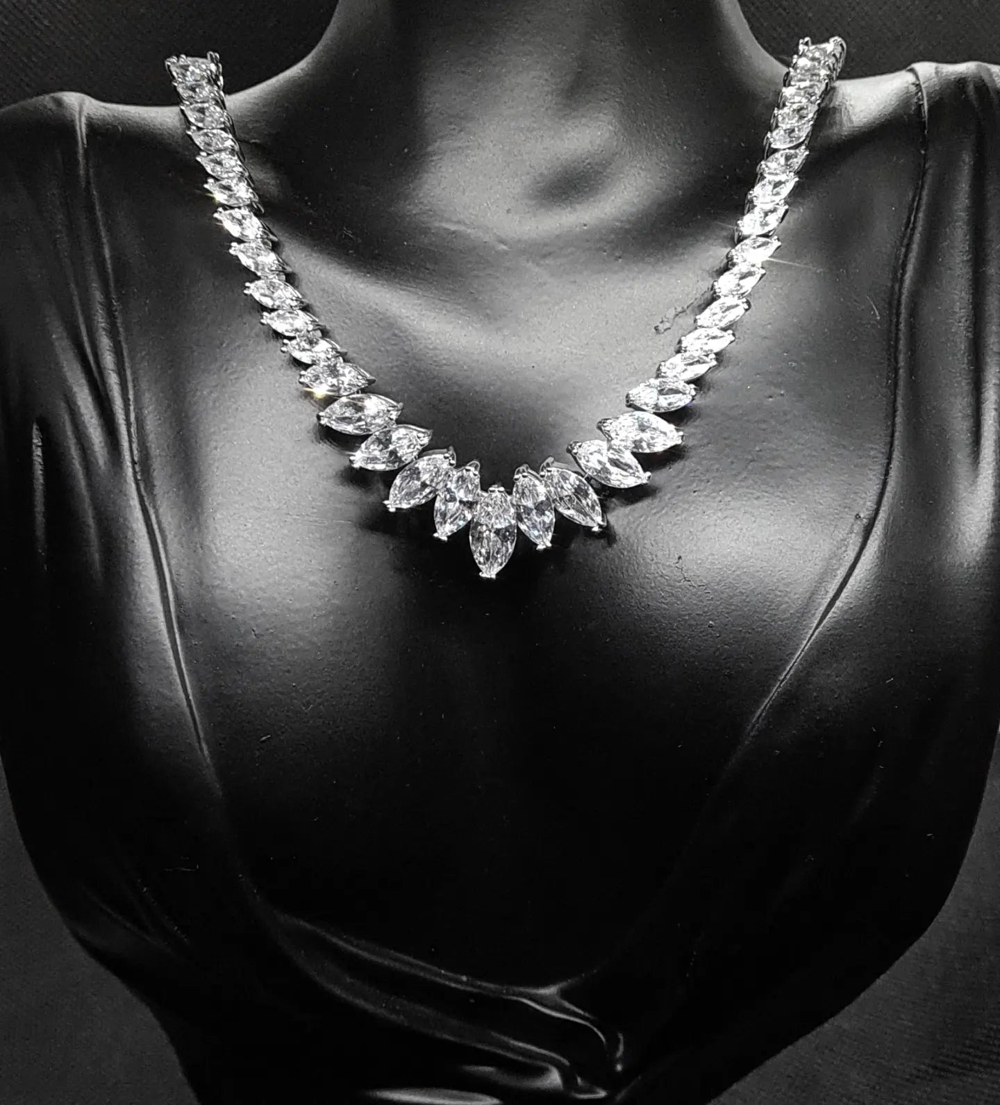 Sparkling cubic zirconia necklace with marquise cut stones on mannequin. The necklace is made up of a single row of marquise-cut cubic zirconia stones, which are sparkling and eye-catching. The necklace is perfect for a special occasion, such as a wedding or prom. It is also a great gift for a loved one.