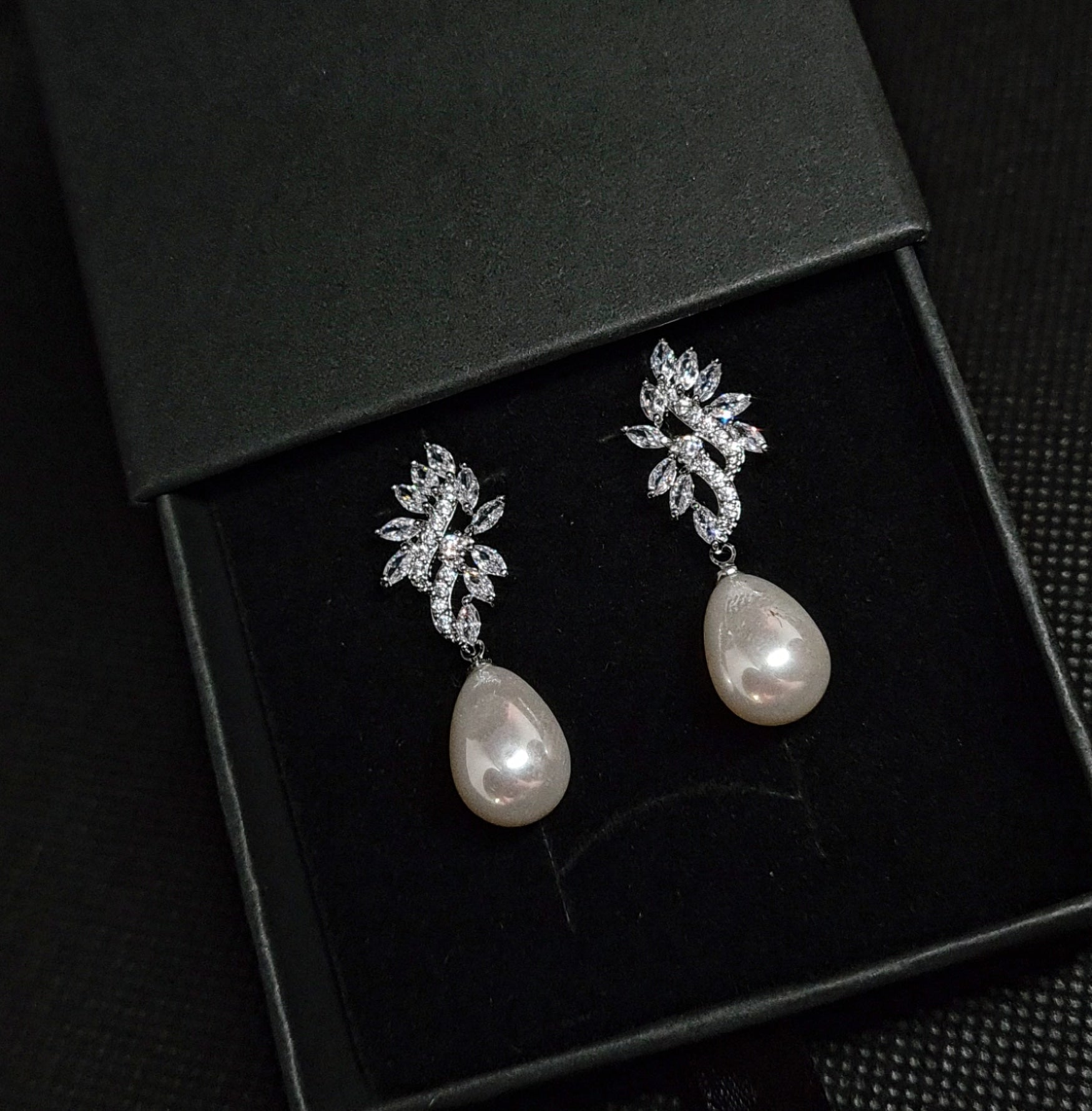 A pair of silver earrings with white pearls. The earrings are simple in design and the pearls are lustrous. The earrings are a perfect accessory for a special occasion or a gift for a loved one.