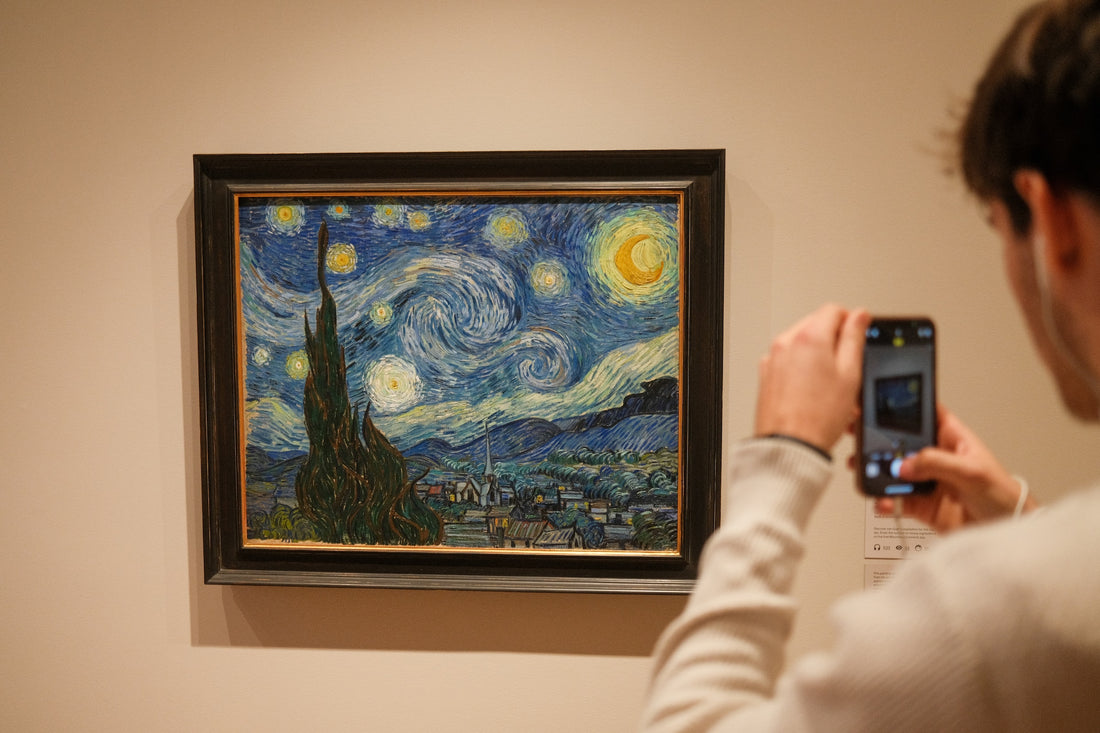 a man taking a photo of a painting on the wall