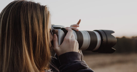 a Women holding a camera taking a shot during daytime photo.