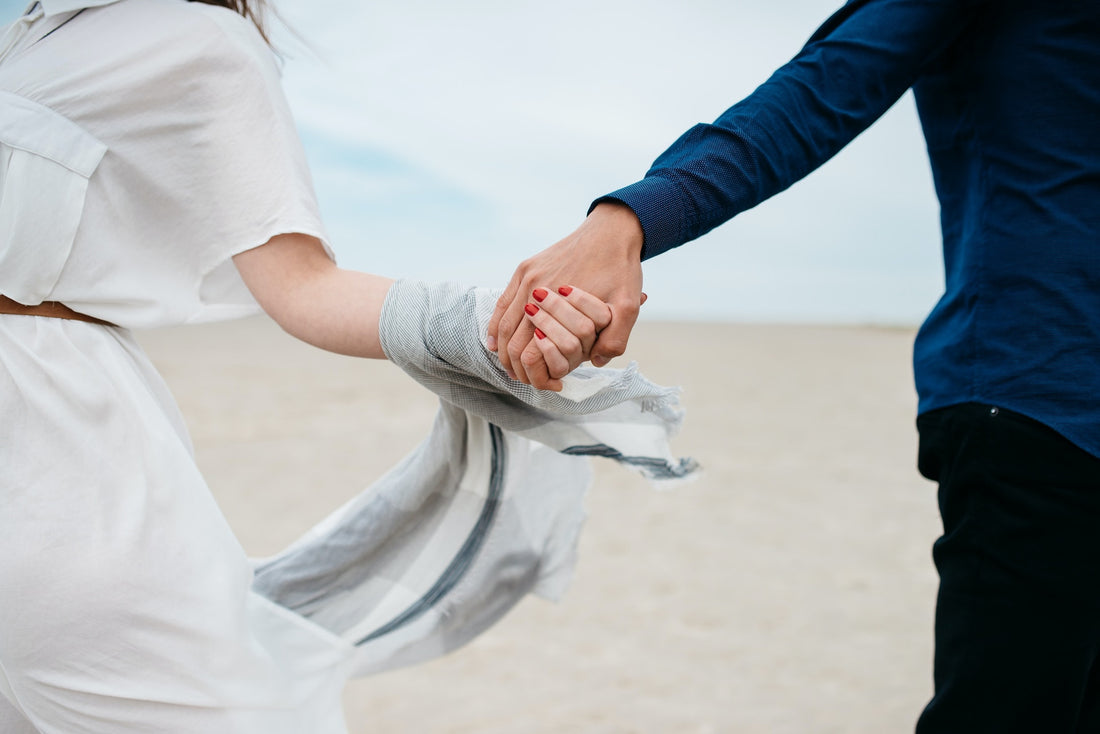 man and woman holding hand in a field of sand under blue sky during daytime photo