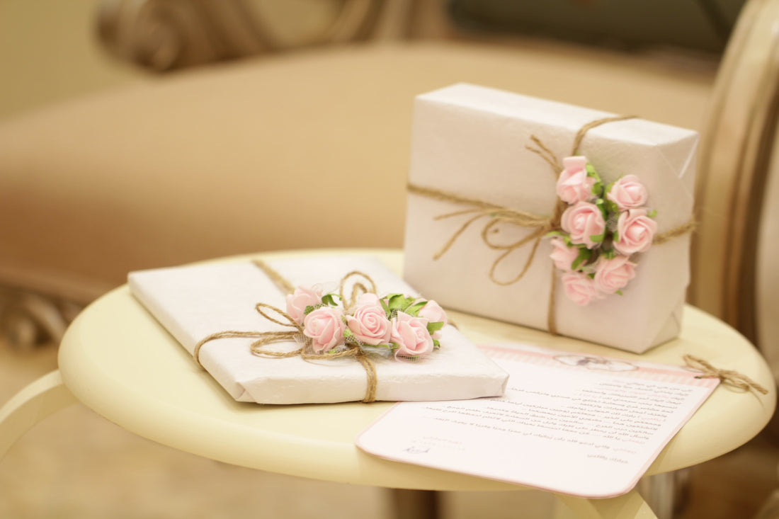 two pink and white flora gift boxes displayed on a table with a side note.