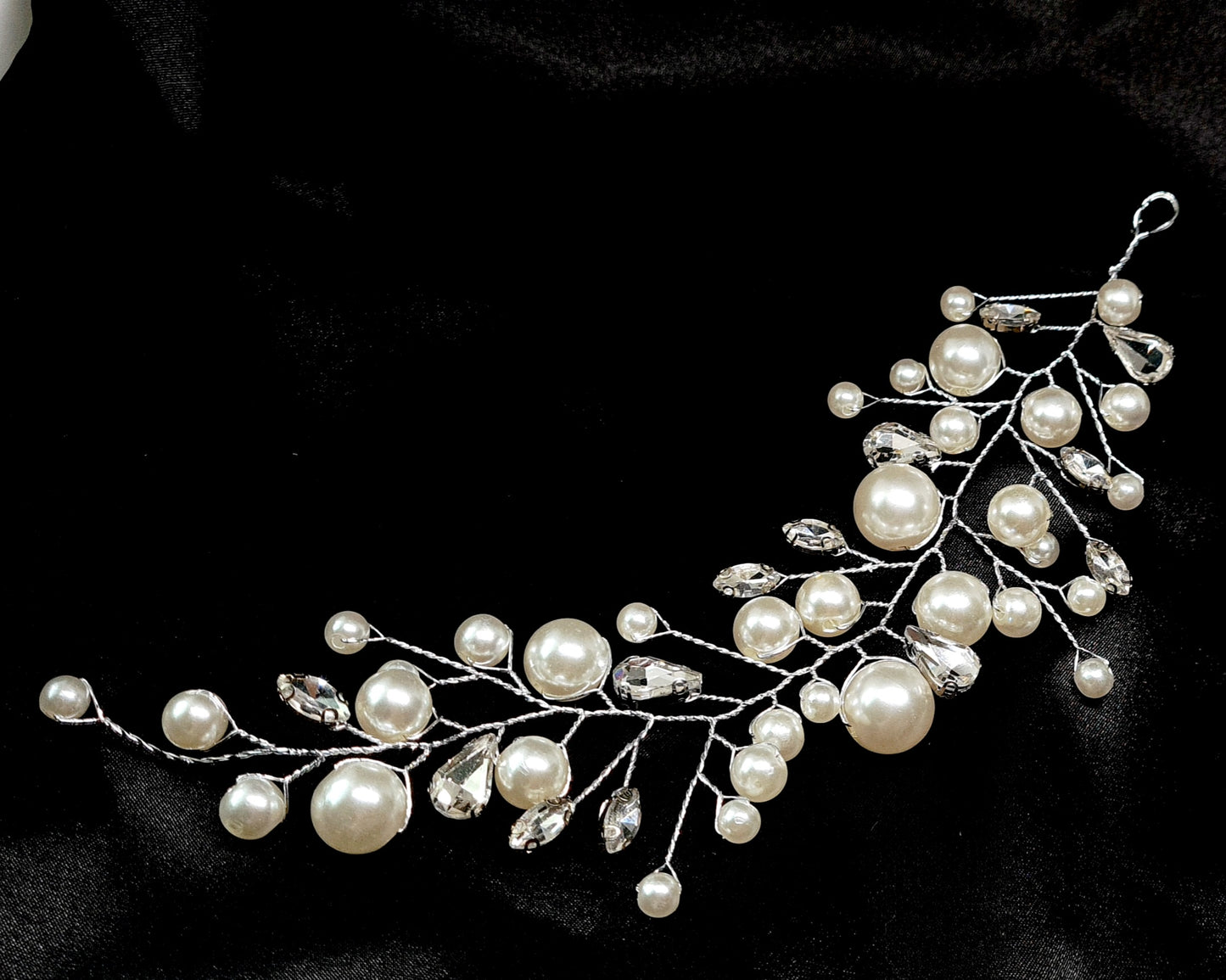 a pearl bridal hair comb on a black background. The hair comb is made of pearls and crystals, and it has a delicate, feminine design. It is perfect for a bride who wants to add a touch of elegance to her wedding day look.