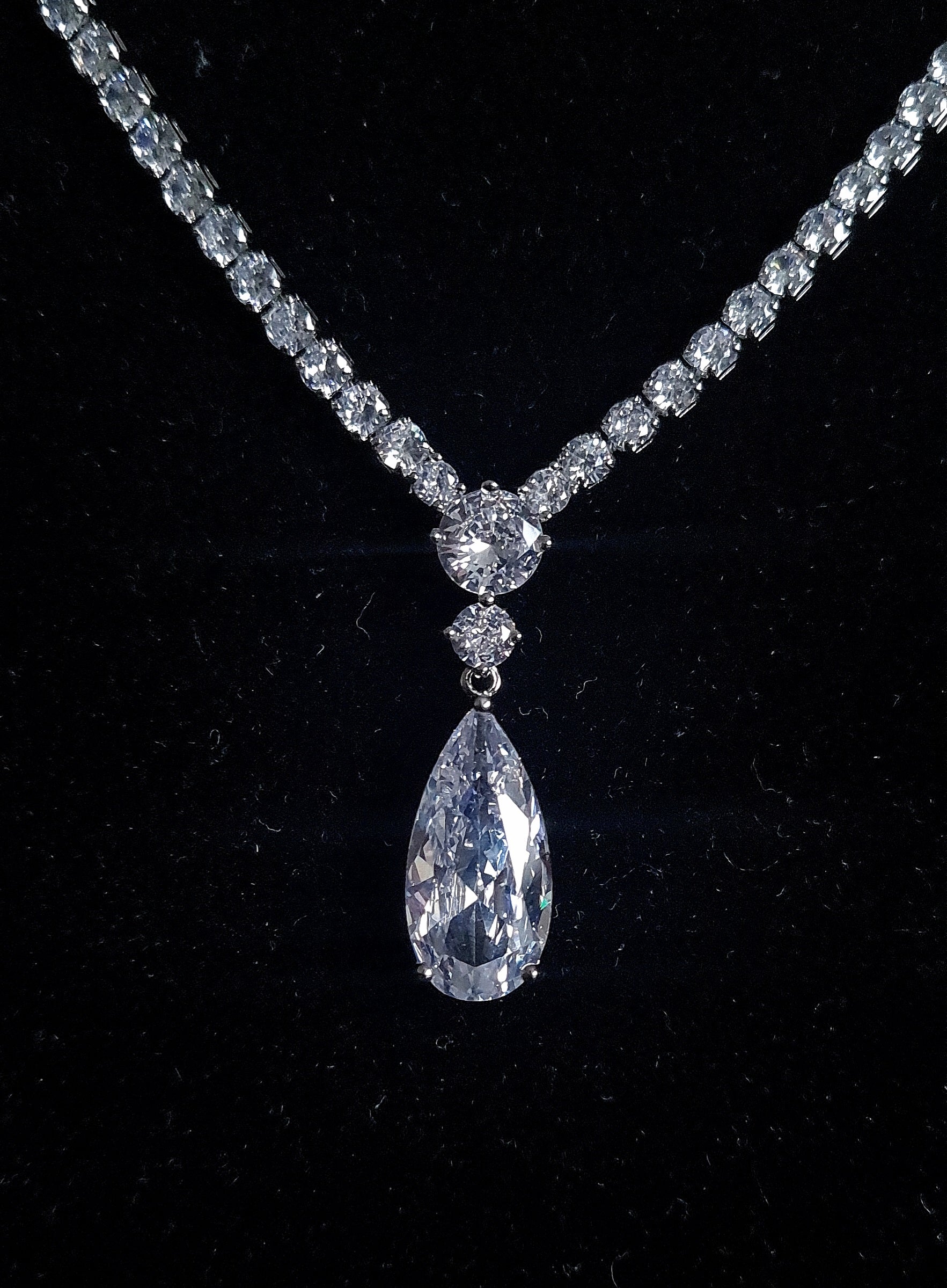 a close up view of a cubic zirconia necklace with teardrop shape center pendent the background is black.