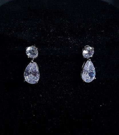 A pair of mini earrings studded with cubic zirconia crystals Placed on black table.