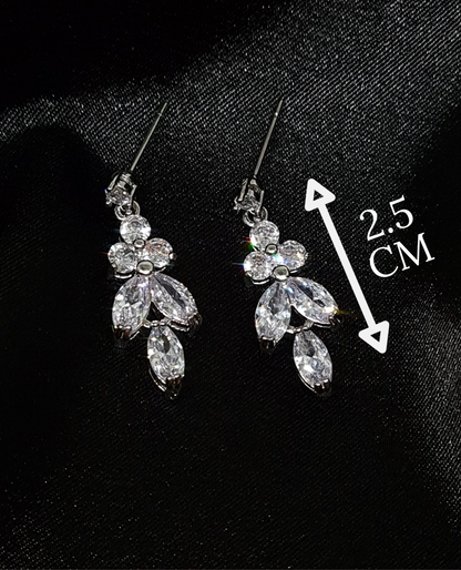 A close-up of a pair of silver earrings with cubic zirconia. The earrings are simple in design, with a modern twist. The cubic zirconia are sparkling and the earrings are a perfect accessory for a special occasion or a gift for a loved one. with measures.