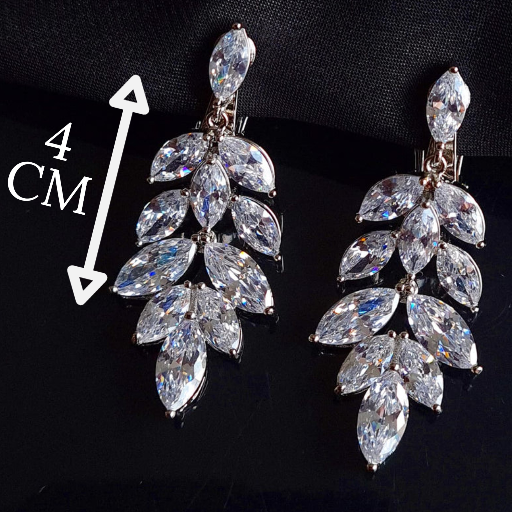 A pair of silver earrings with cubic zirconia. The earrings are simple in design and the cubic zirconia are sparkling. The earrings are a perfect accessory for a special occasion or a gift for a loved one. with measures.