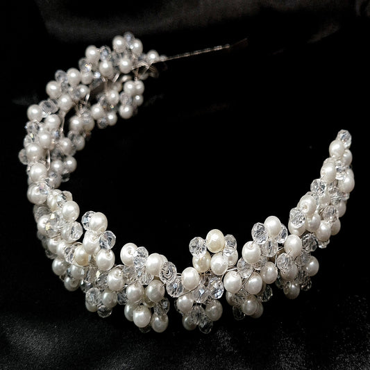 A headband made of pearls and crystals on a black background. The headband is decorated with sparkling crystals and pearls. The headband is perfect for a special occasion or for everyday wear.