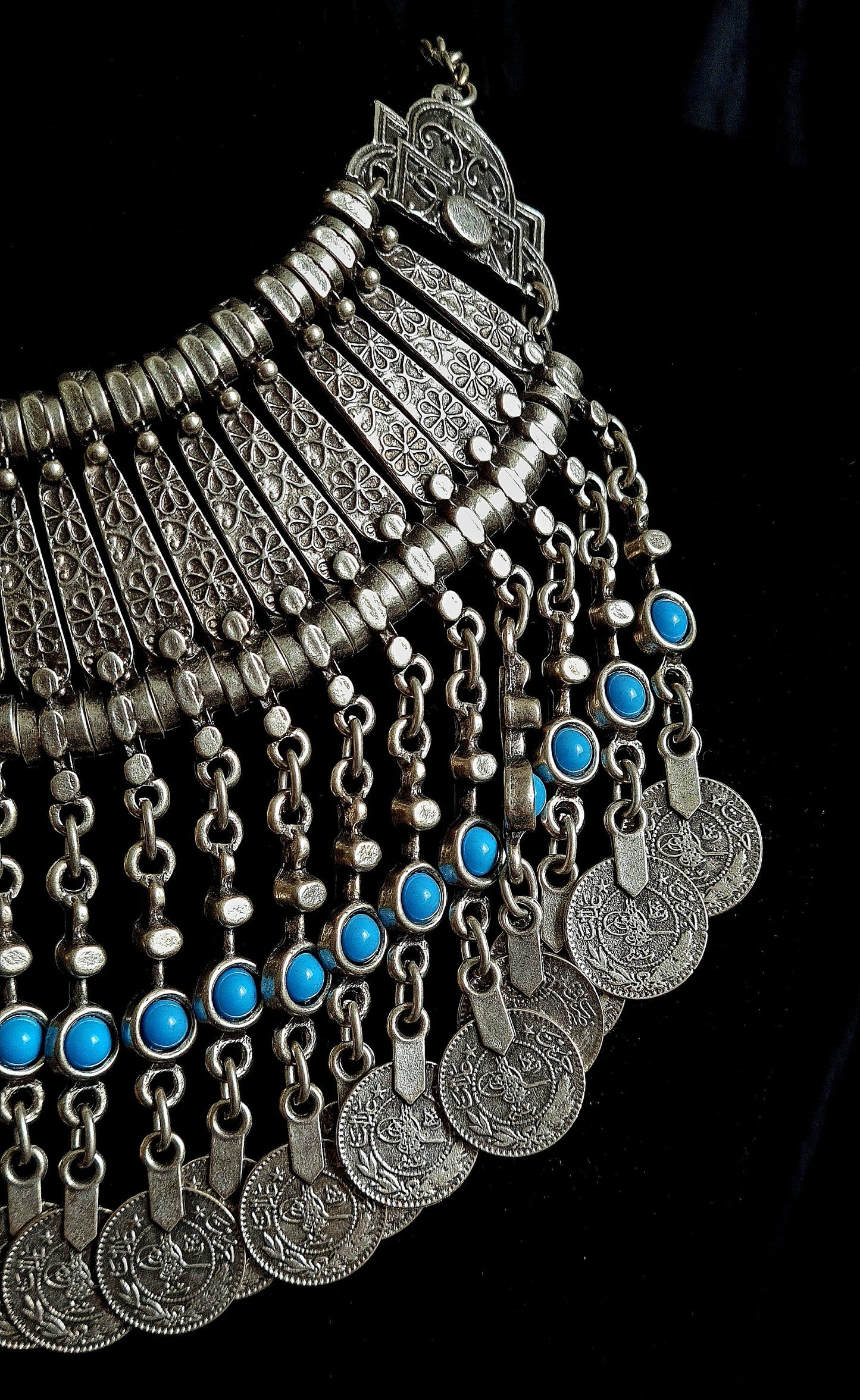 Close-up shot photography of the Priscilla filigree necklace showcasing meticulous metalwork, floral engravings, and vibrant turquoise cabochons on a black velvet background