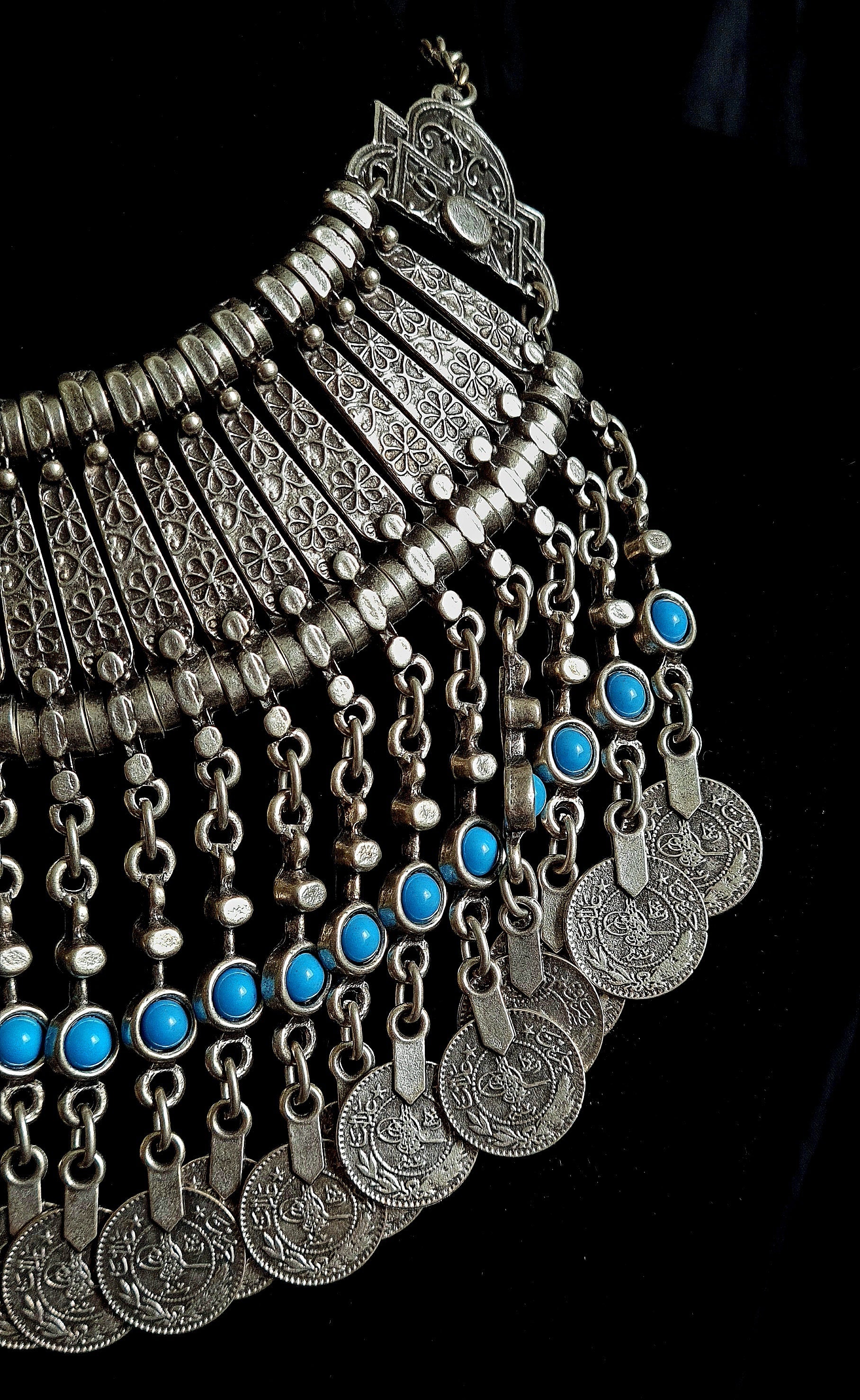 Close-up shot photography of the Priscilla filigree necklace showcasing meticulous metalwork, floral engravings, and vibrant turquoise cabochons on a black velvet background