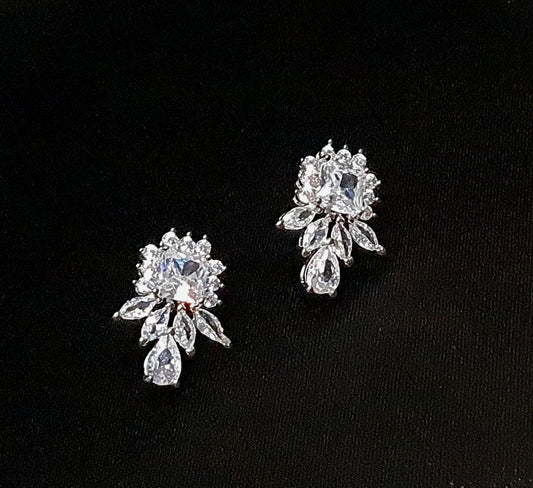 A pair of cubic zirconia earrings with a princess-cut center stone. The earrings are teardrop-shaped and have a simple, elegant design. The cubic zirconia stones are clear and sparkling. The earrings are sitting on a black surface.