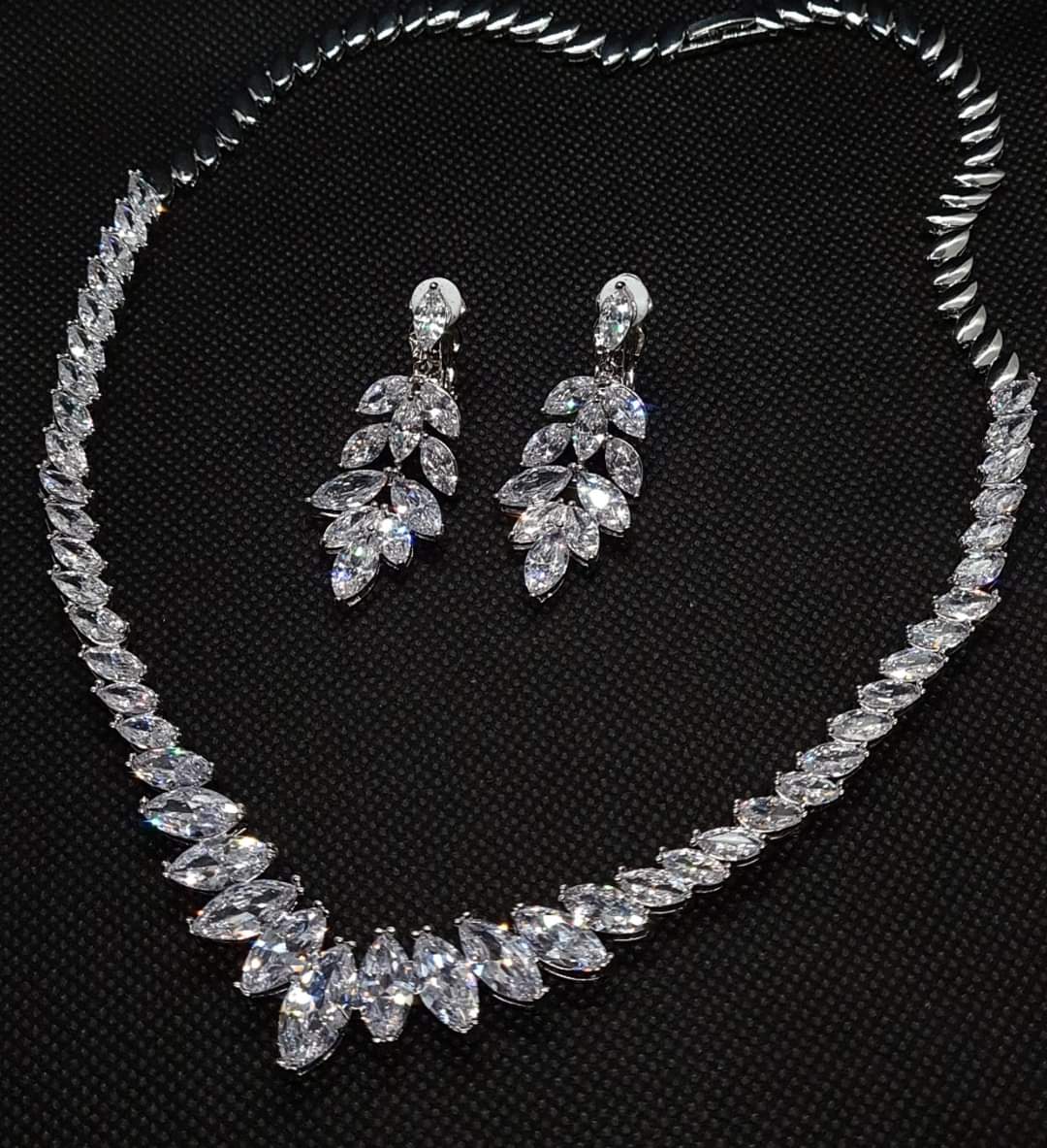 a Stylish Cubic Zirconia Necklace and Earring Jewelry Set with Marquise Cut Design. The Necklace Showcases a Brilliant Marquise Shape Cut CZ Pendant, Complemented by Dangle Drop Earrings of Matching Design. All Set Against a Sleek Black Background,