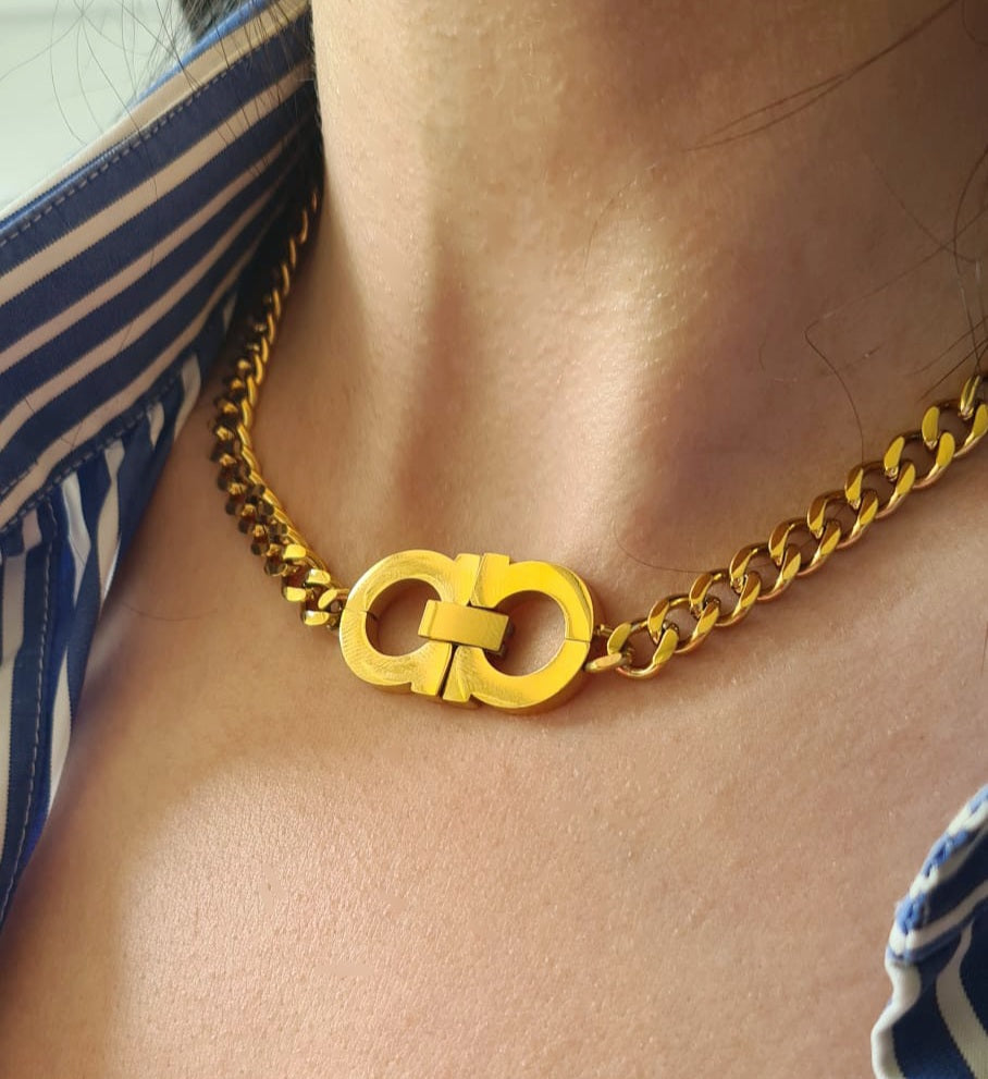 a woman wearing a A gold chain necklace with the letter C, The necklace is made of gold and has a simple design. The letter C is large and has a polished finish. The necklace is elegant and understated.