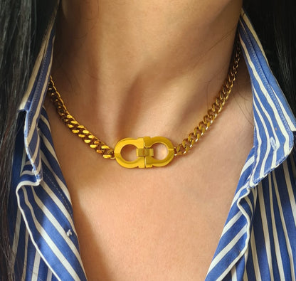 a woman wearing a A gold chain necklace with the letter C, The necklace is made of gold and has a simple design. The letter C is large and has a polished finish. The necklace is elegant and understated.