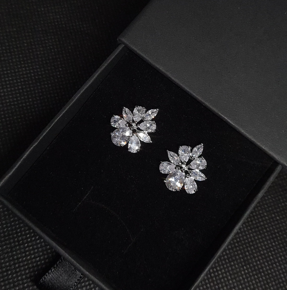 A pair of silver earrings with white diamonds. The earrings are simple in design and the diamonds are sparkling. These elegant earrings would be perfect for a special occasion and would make a great gift.