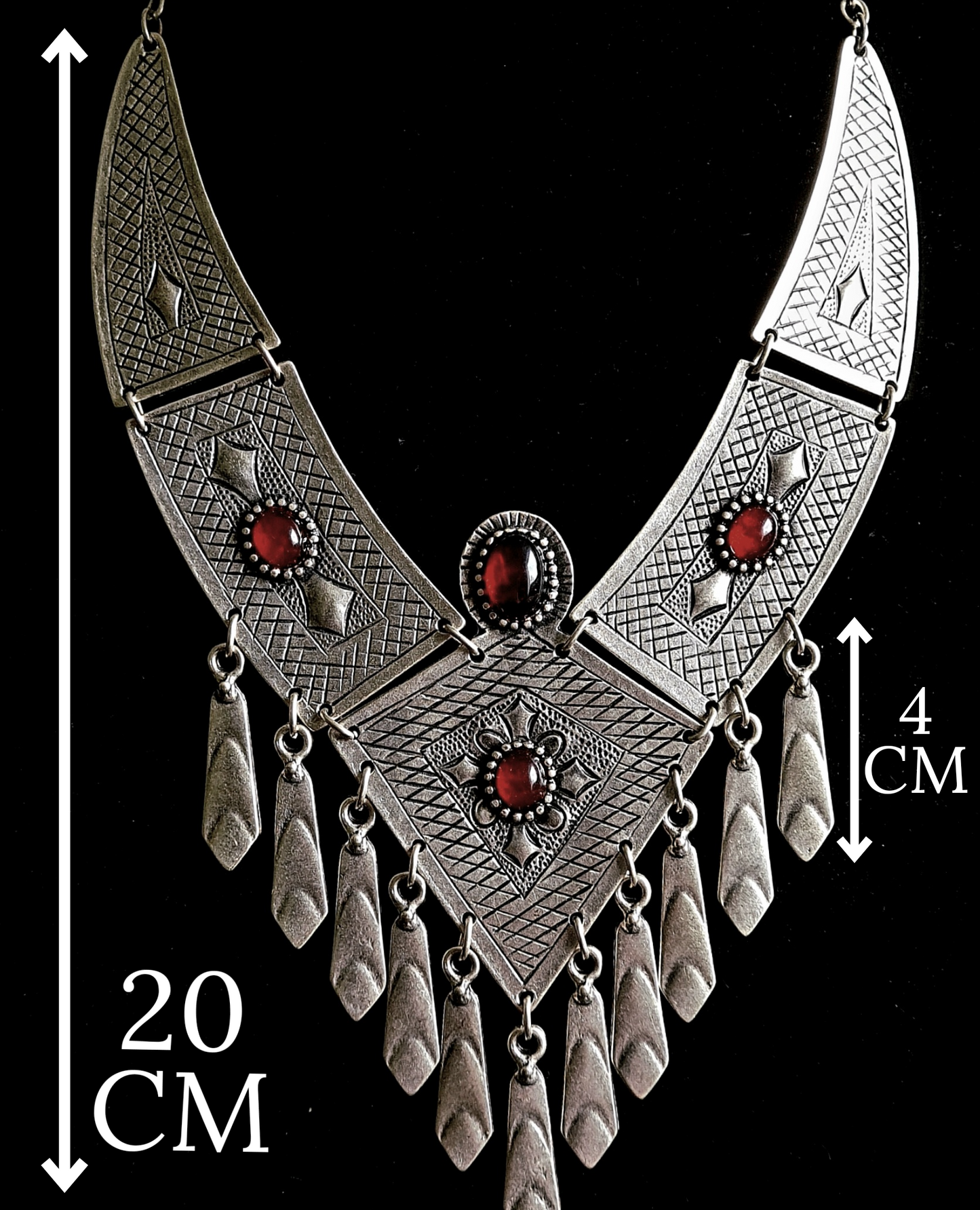 A silver necklace with red stones on a black background. The necklace is made of silver and has a delicate design. The red stones are round and have a deep red color. The necklace is long and hangs down to the chest. with measurements.
