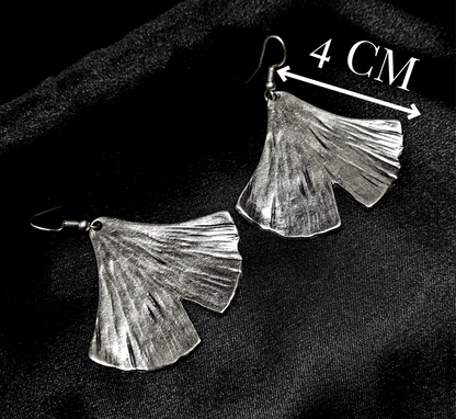 A pair of silver earrings in the shape of a ginkgo leaf sitting on a black surface. The earrings are small and delicate, and they have a shiny finish. The ginkgo leaf is fan-shaped and has a textured appearance ith measurements.