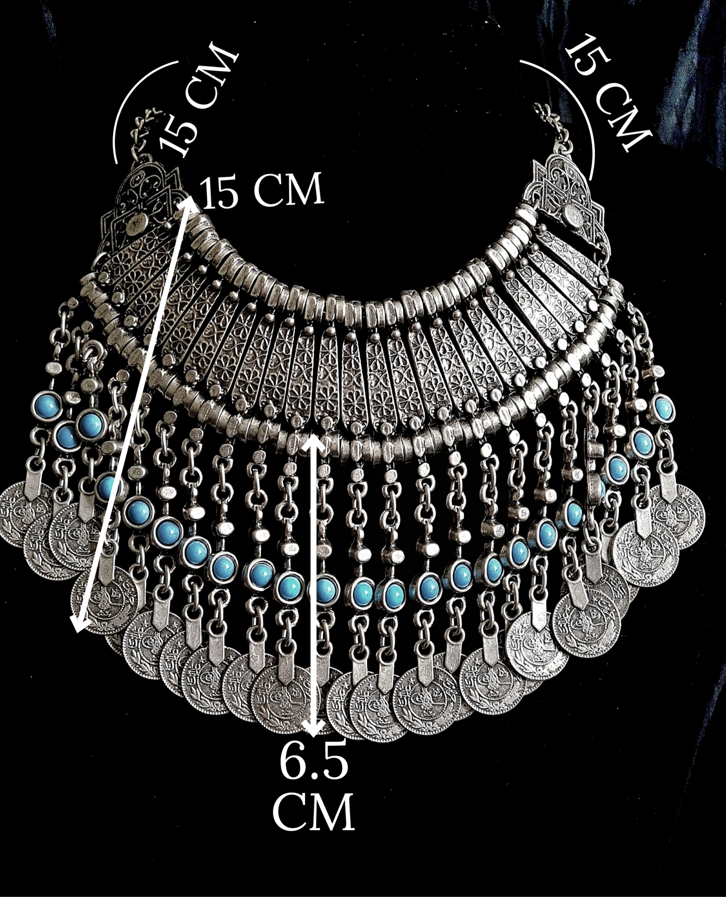 A silver necklace with turquoise beads and coins on a black background. The necklace is made of silver and has a delicate design. The turquoise beads are small and round, and they have a bright blue color. The coins are also small and round, and they have a bronze color. The necklace is long and hangs down to the chest. with measurements.