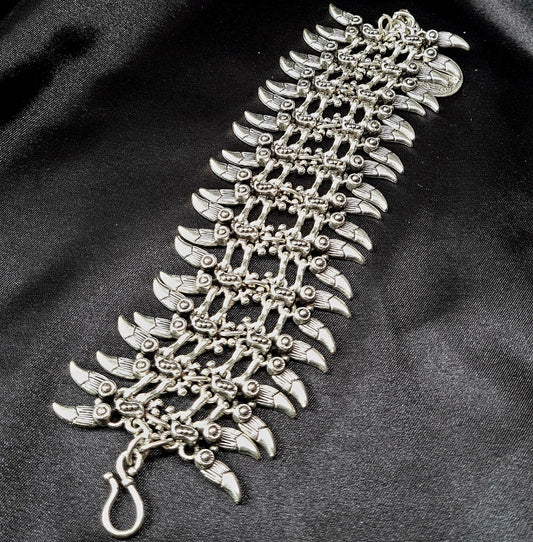 Professional studio shot of a wide artisan silver spike cuff bracelet with intricate bohemian engravings, displayed on a seamless matte black background for a luxury jewelry catalog.