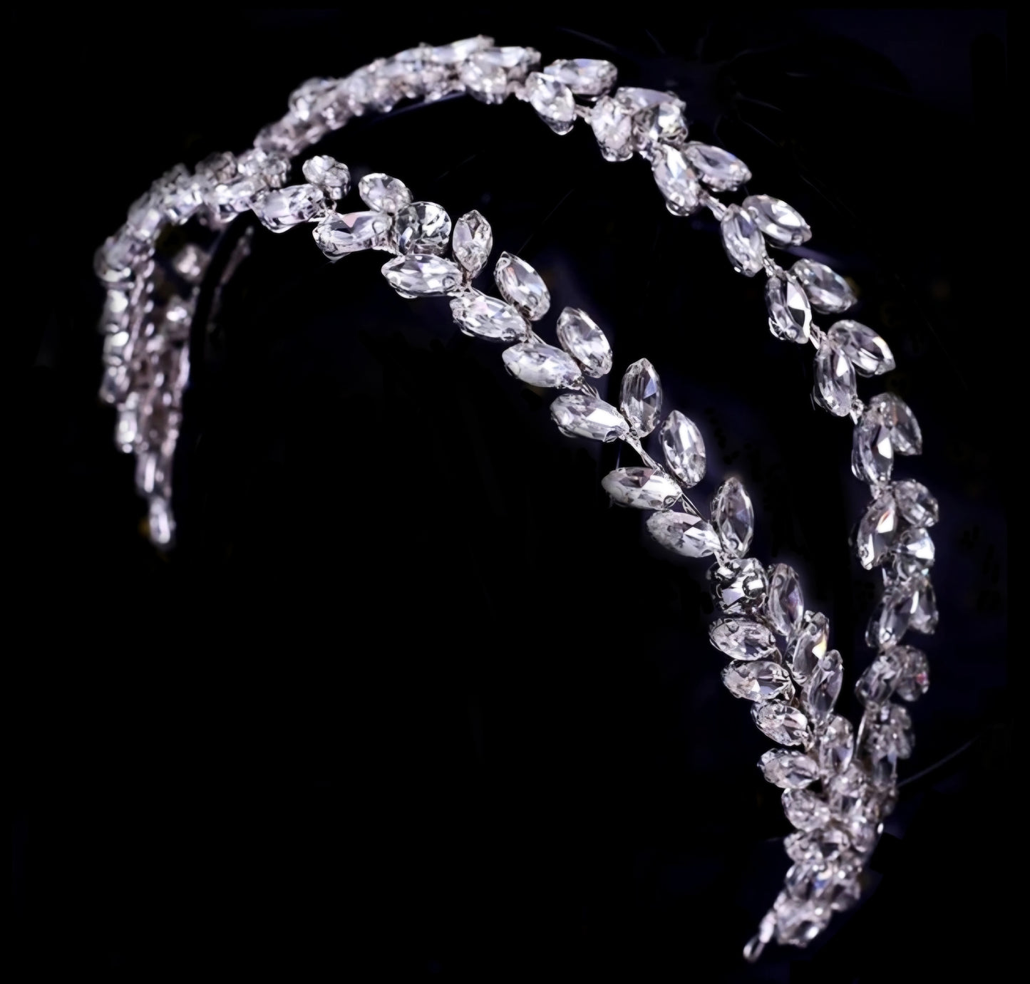 A sophisticated double-row headband featuring leaf-shaped marquise crystals in a repeating pattern, set against a deep black background for a luxury fashion campaign feel.